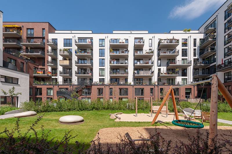 Begrünter Innenhof von Dock 71 mit Spielplatz und Wiese zwischen den Wohnhäusern
