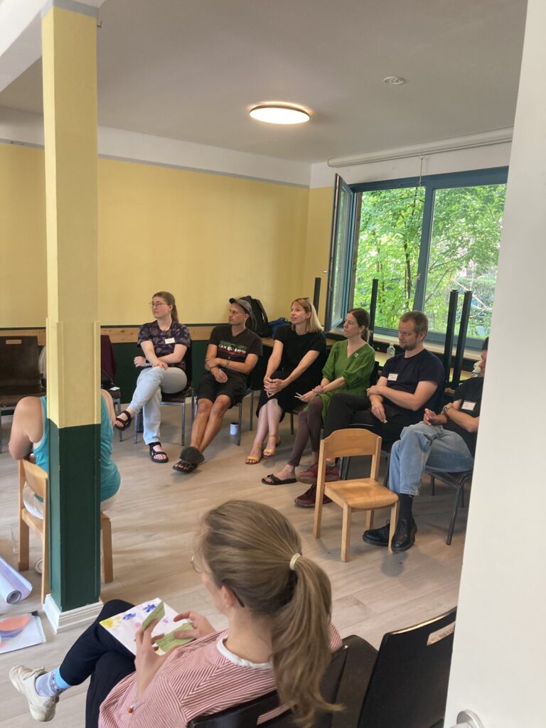 Workshop des Inselkiez e. V.: Mitglieder sitzen im Stuhlkreis in einem hellen Raum mit gelben Wänden